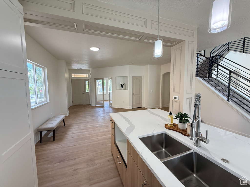 Kitchen with a sink, light wood-style floors, healthy amount of natural light, light stone counters, and recessed lighting