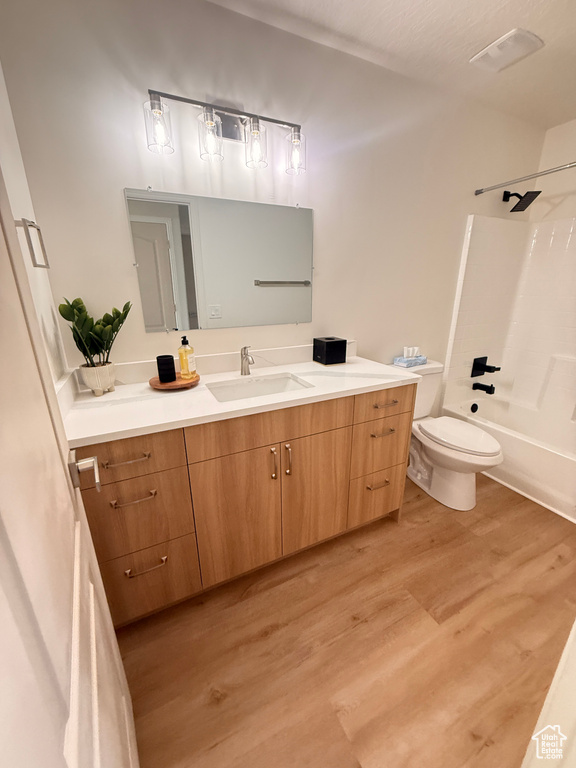 Bathroom featuring wood finished floors, vanity, toilet, and shower / bath combination