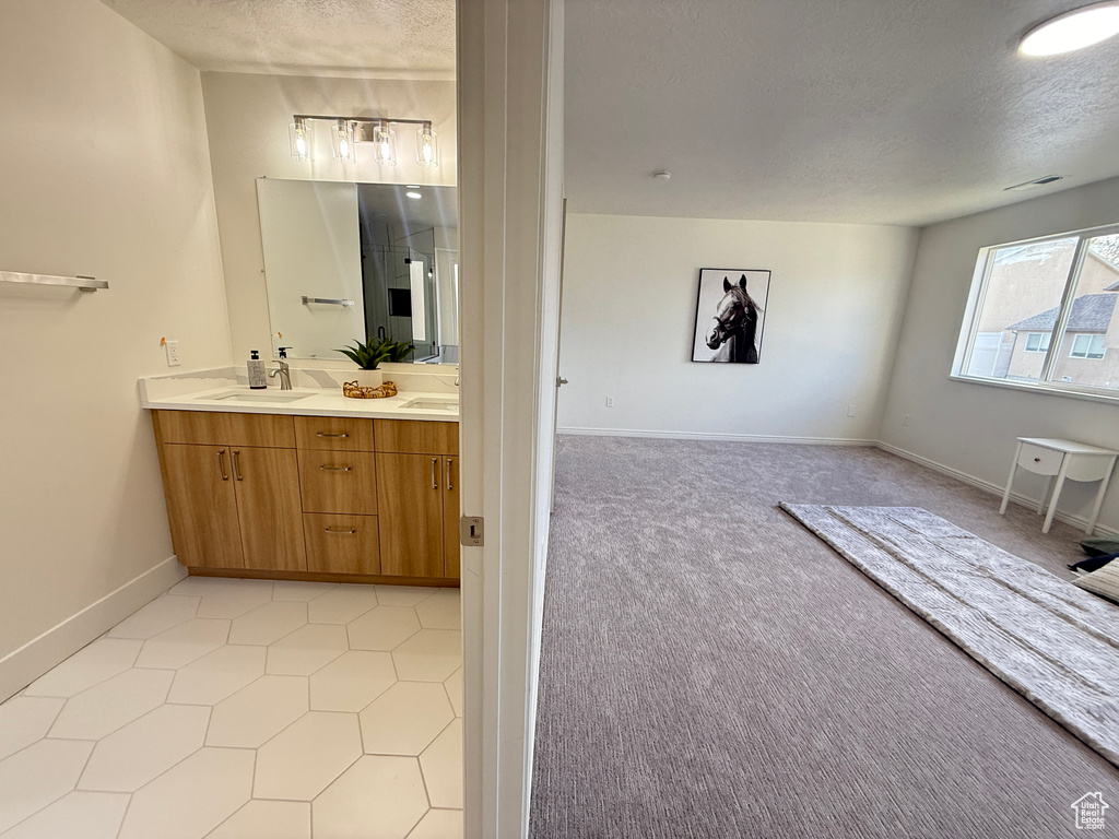Bathroom featuring a textured ceiling, double vanity, baseboards, and tile patterned flooring