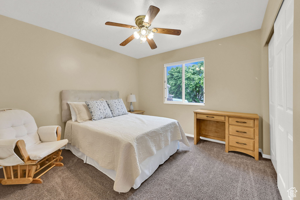 Bedroom featuring a closet, light colored carpet, baseboards, and ceiling fan