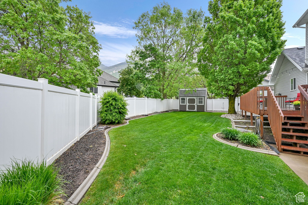 View of yard featuring a wooden deck, a shed, an outdoor structure, and stairway