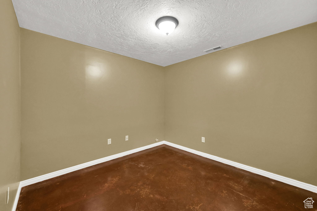 Spare room featuring concrete floors, a textured ceiling, and baseboards