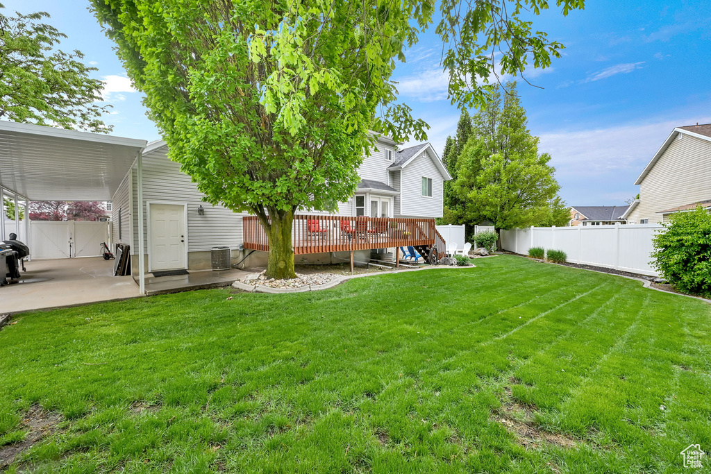 View of yard with a wooden deck and a patio