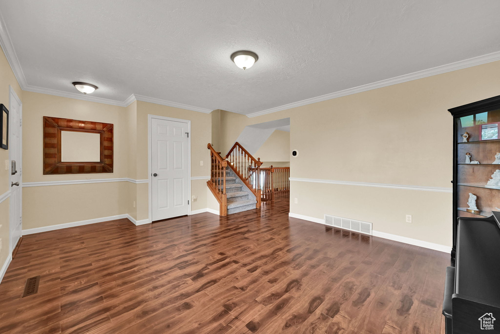 Spare room with stairs, wood finished floors, ornamental molding, baseboards, and a textured ceiling
