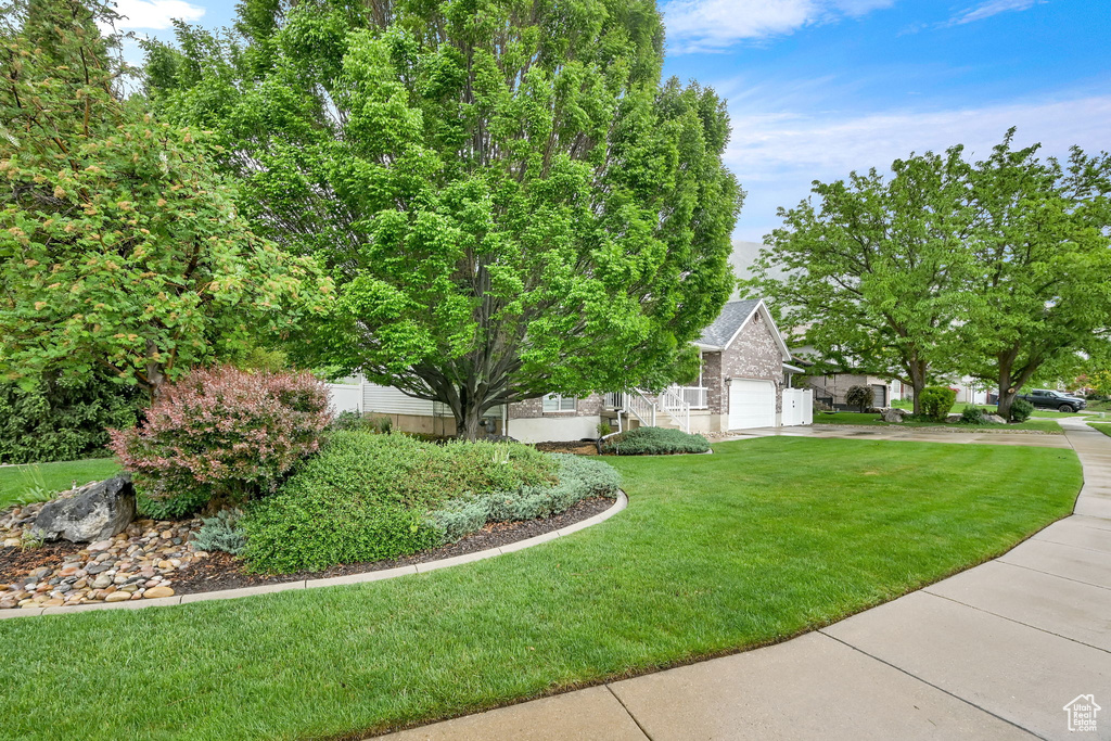 View of grassy yard with concrete driveway and a garage