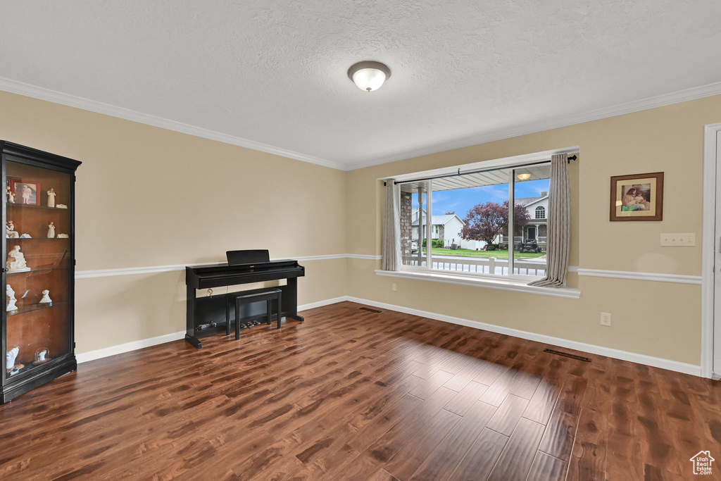Spare room with wood finished floors, ornamental molding, baseboards, and a textured ceiling