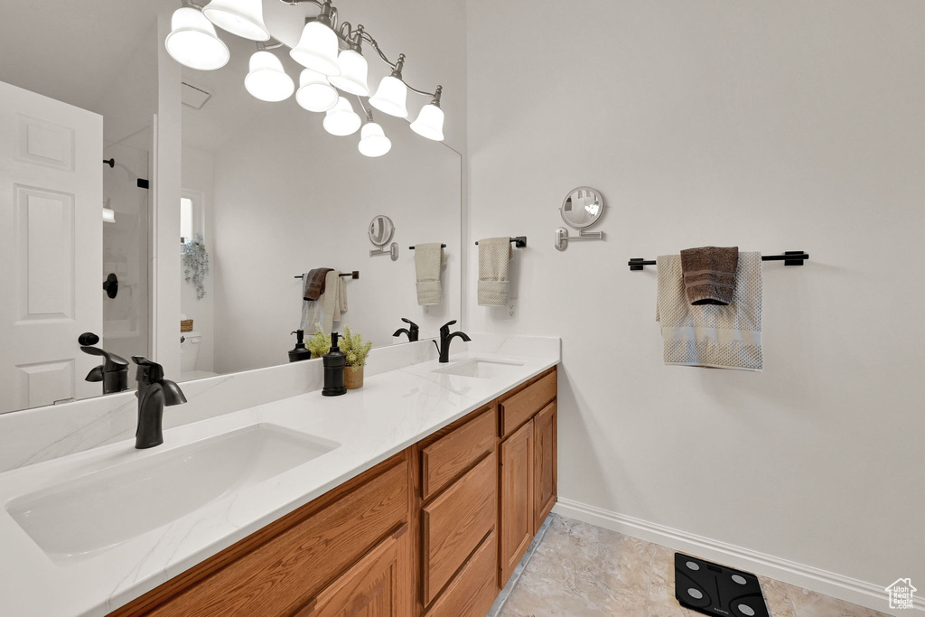Full bath with a shower, toilet, double vanity, and baseboards