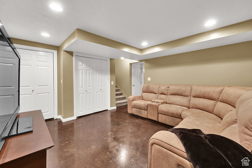 Living area with finished concrete floors, baseboards, stairway, and recessed lighting