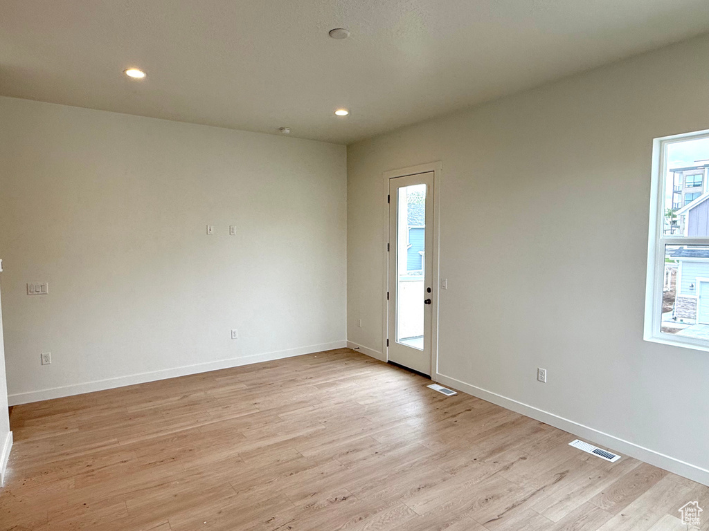 Empty room with plenty of natural light, light wood-style flooring, baseboards, and recessed lighting
