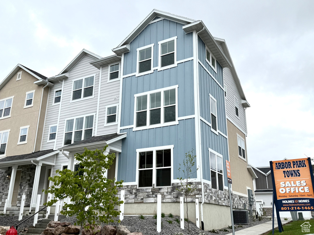 View of side of home featuring board and batten siding, stone siding, and central air condition unit