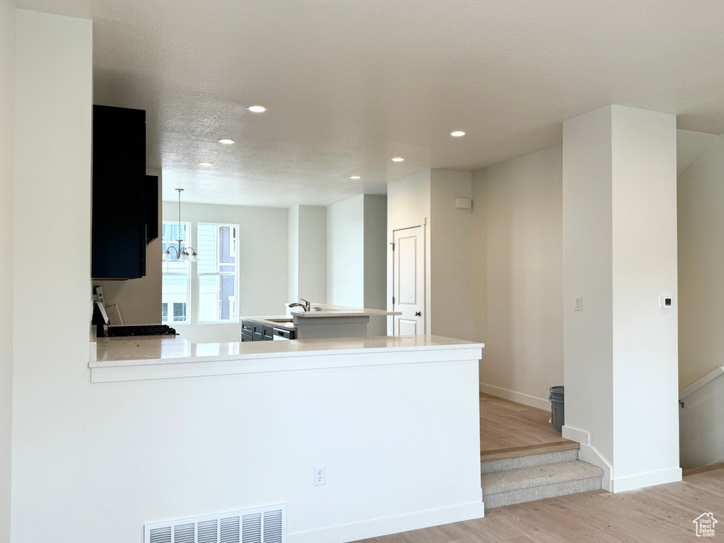 Kitchen with recessed lighting, light wood finished floors, stove, baseboards, and light countertops