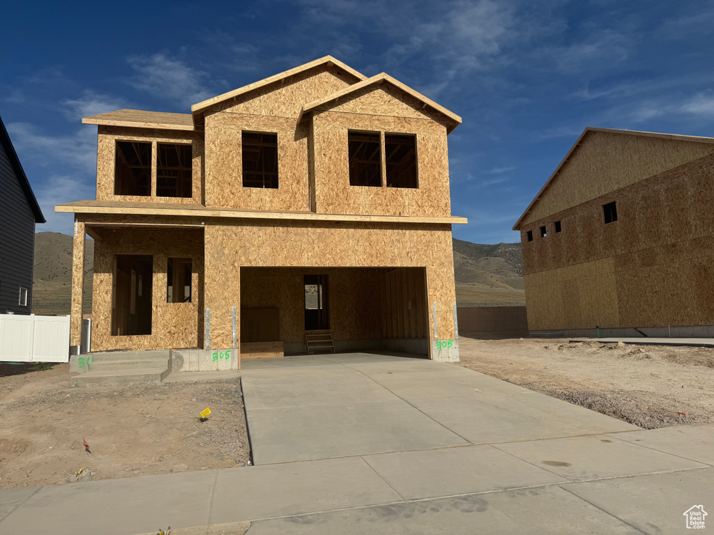 Property under construction with driveway, a garage, a mountain view, and covered porch