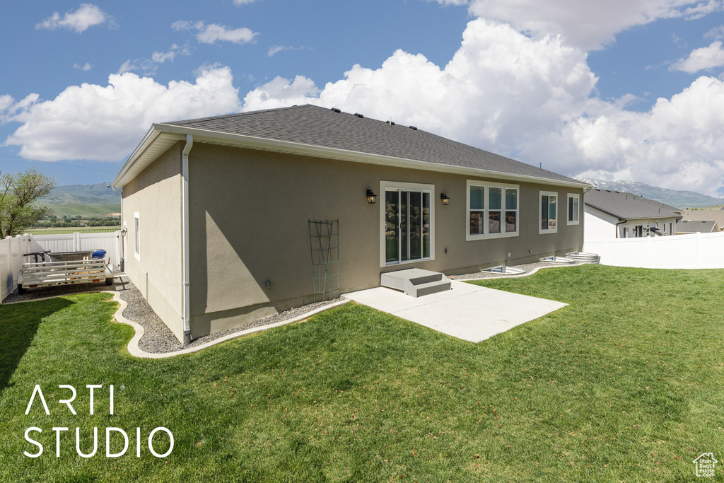 Back of property featuring stucco siding, roof with shingles, a patio area, and a mountain view