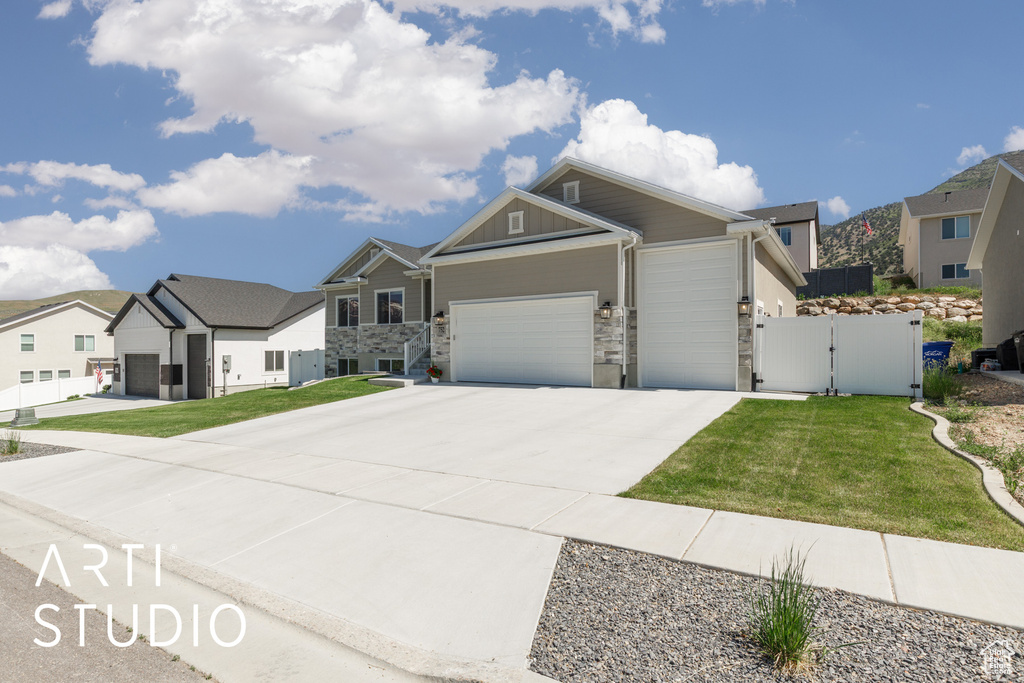 View of front of house featuring a gate, an attached garage, stone siding, driveway, and a residential view
