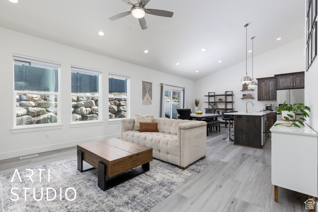 Living room with lofted ceiling, a ceiling fan, light wood-style flooring, recessed lighting, and baseboards