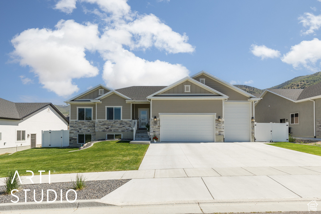 Craftsman house with a gate, stone siding, an attached garage, and concrete driveway