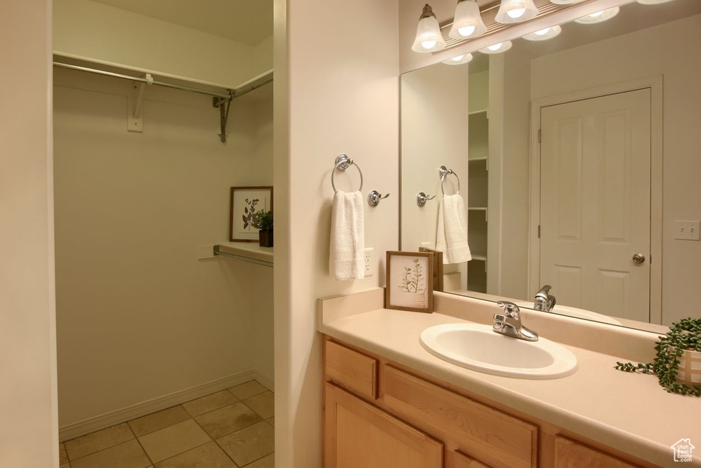 Bathroom with tile patterned floors, a walk in closet, vanity, and baseboards