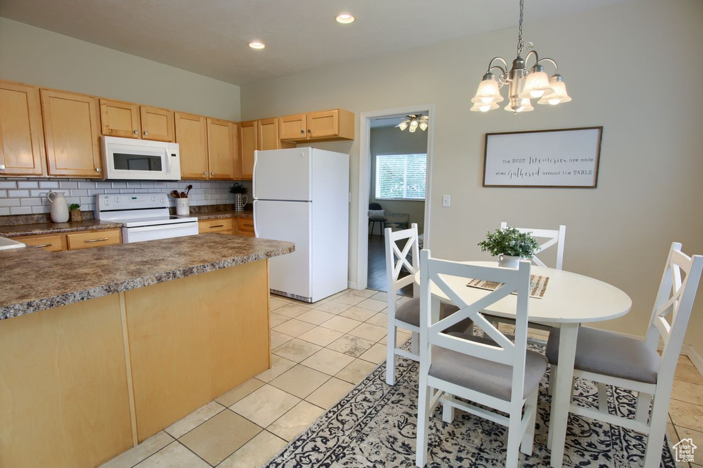 Kitchen featuring white appliances, light brown cabinetry, tasteful backsplash, a chandelier, and dark countertops