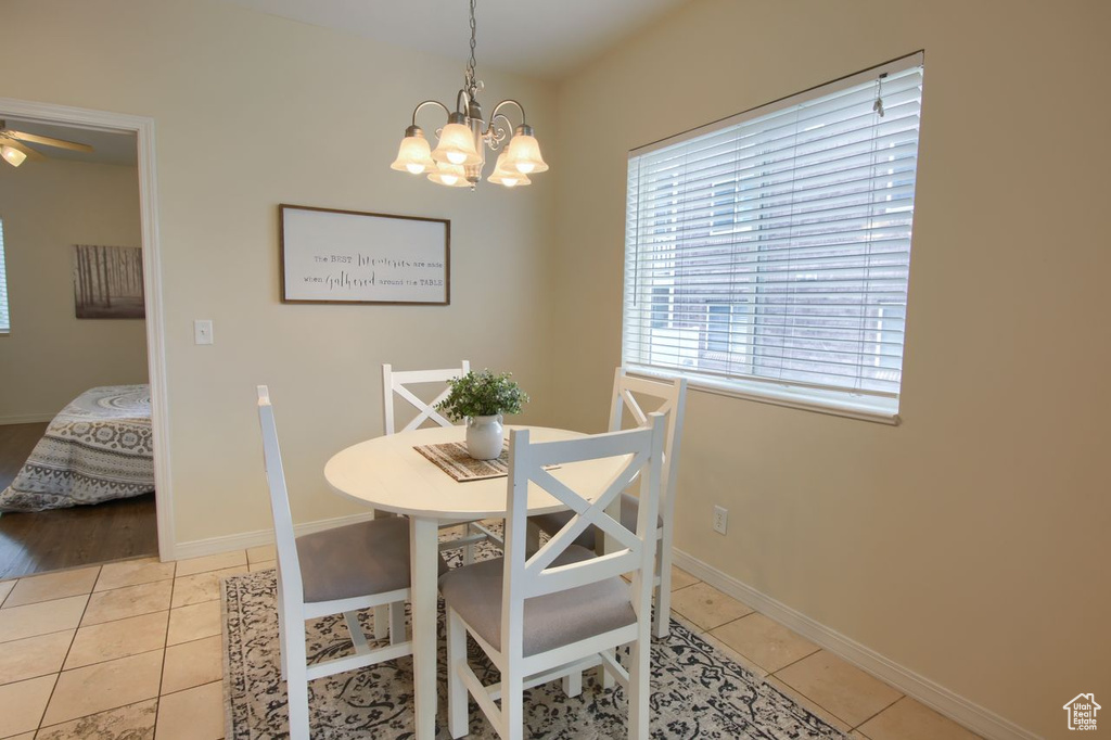 Dining area with a chandelier, light tile patterned floors, baseboards, and a ceiling fan