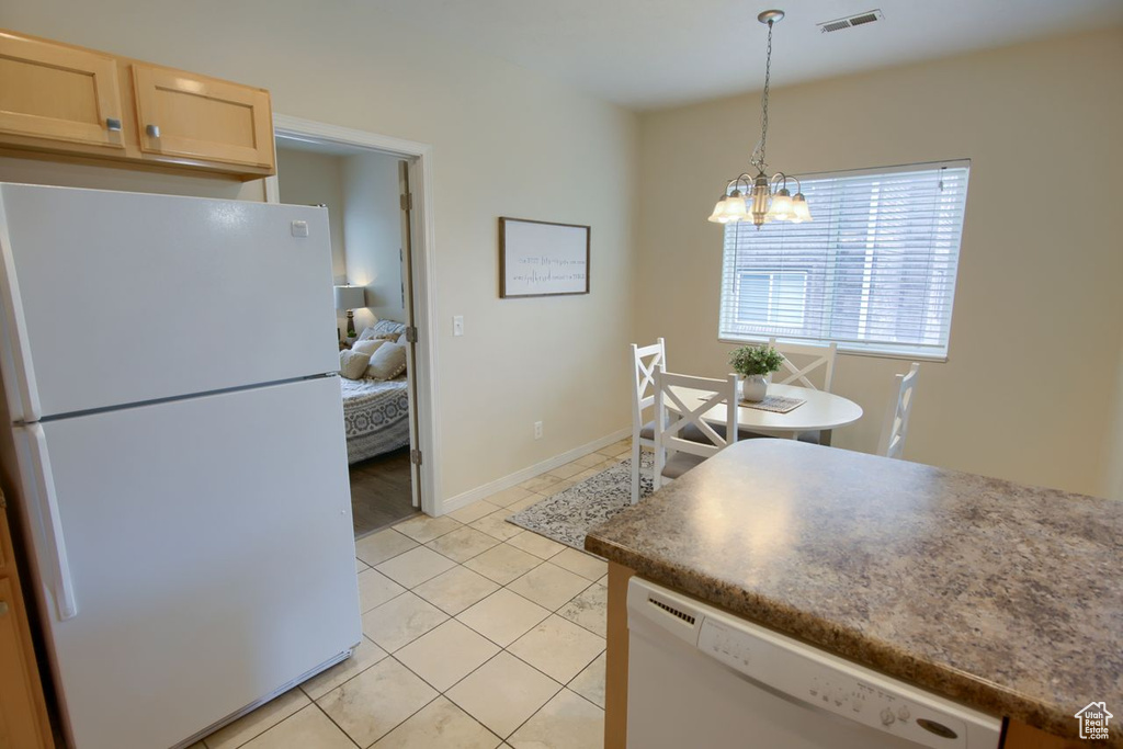 Kitchen featuring white appliances, a chandelier, light tile patterned flooring, decorative light fixtures, and light brown cabinetry