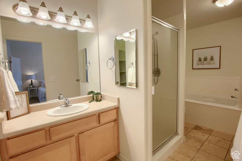 Full bath featuring a stall shower, vanity, ensuite bath, and tile patterned flooring