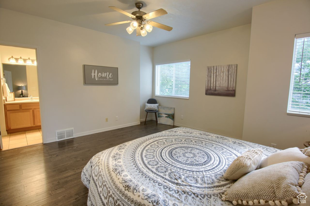 Bedroom with wood finished floors, baseboards, ensuite bath, a sink, and ceiling fan