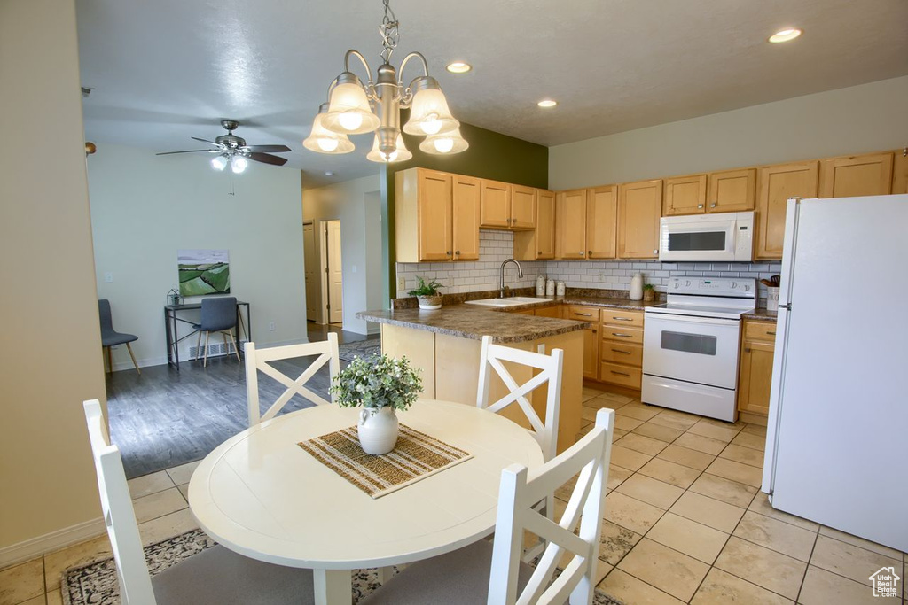 Kitchen with white appliances, light brown cabinetry, a sink, backsplash, and a chandelier