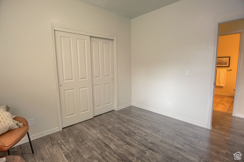 Unfurnished bedroom with dark wood-style flooring, a closet, and baseboards