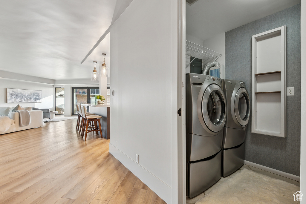 Laundry room with separate washer and dryer, light wood finished floors, and baseboards