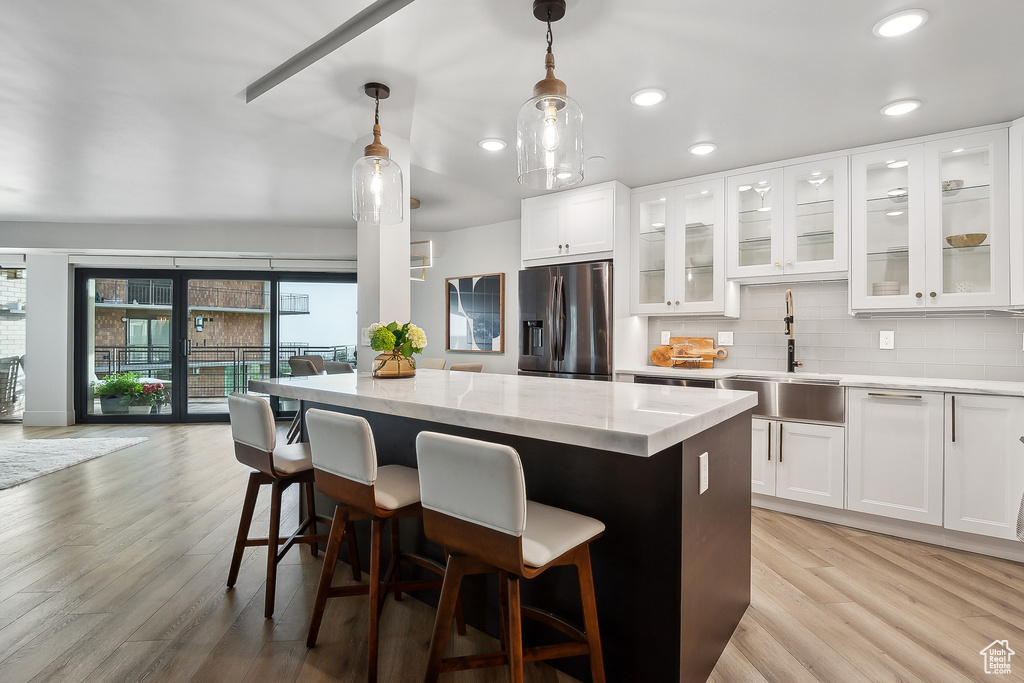 Kitchen featuring stainless steel refrigerator with ice dispenser, a sink, a center island, light wood finished floors, and recessed lighting