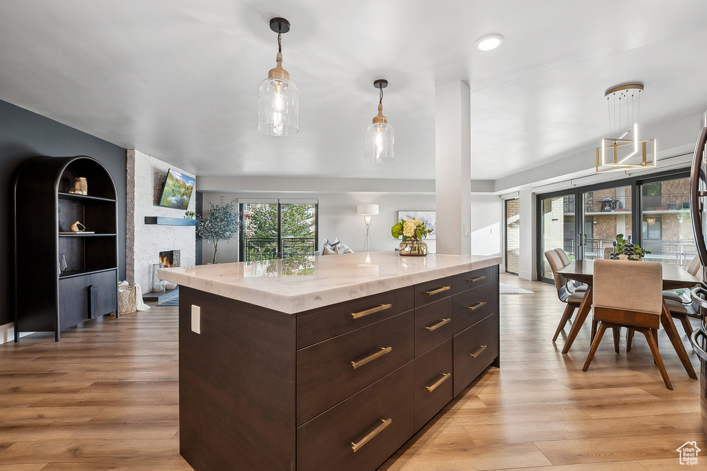 Kitchen with light wood-style floors, decorative light fixtures, dark brown cabinetry, and modern cabinets