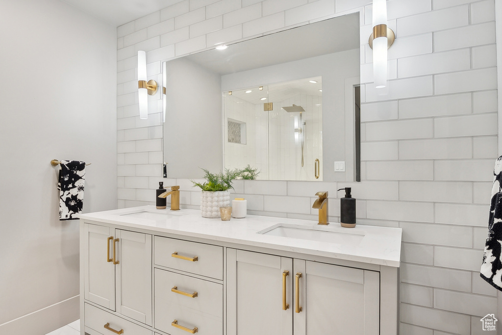 Bathroom featuring backsplash, a shower stall, and double vanity