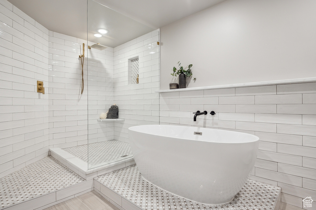 Bathroom with tile walls, a tile shower, a soaking tub, and recessed lighting