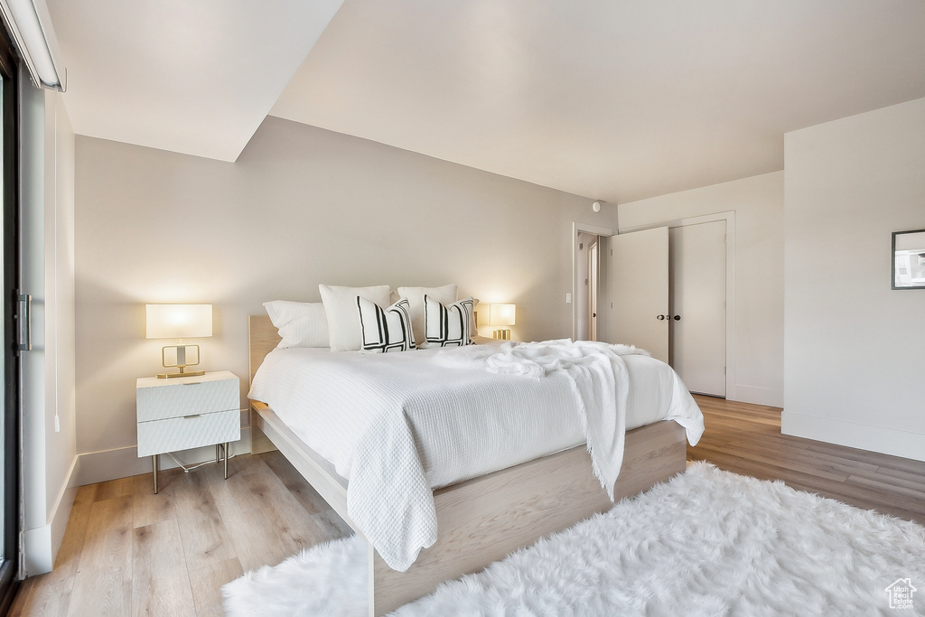 Bedroom with wood finished floors, baseboards, and a closet