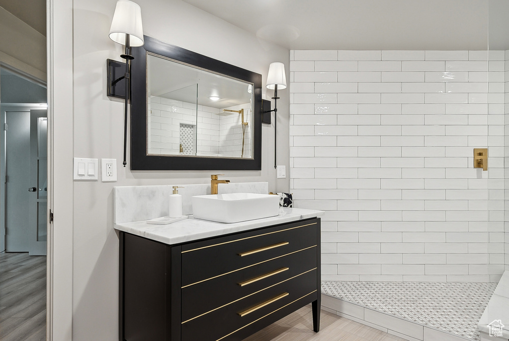 Full bath with tiled shower and vanity