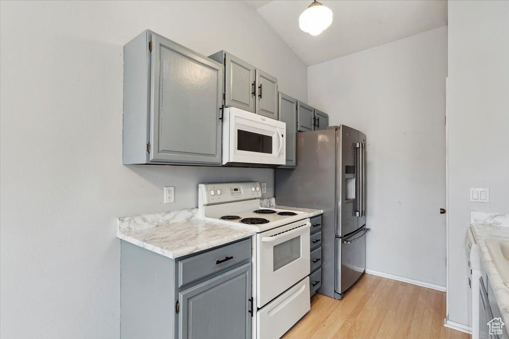 Kitchen featuring white appliances, gray cabinetry, light wood-type flooring, light countertops, and baseboards