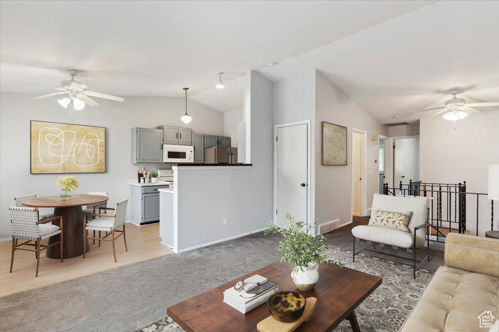 Carpeted living room with ceiling fan and vaulted ceiling