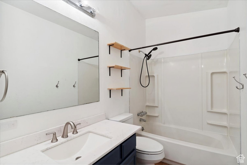 Bathroom featuring toilet, vanity, and shower / tub combination