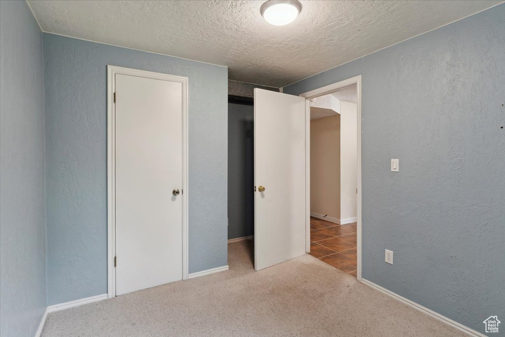 Unfurnished bedroom featuring a textured ceiling, a textured wall, and carpet floors