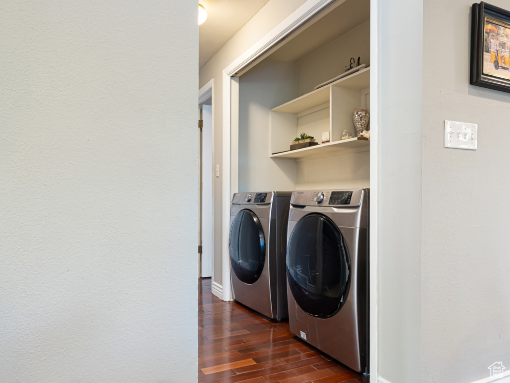 Washroom with dark wood finished floors, separate washer and dryer, and baseboards