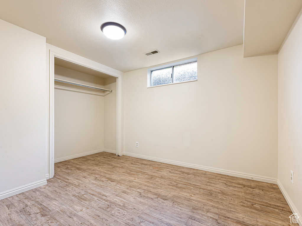 Unfurnished bedroom with light wood-type flooring, baseboards, and a closet