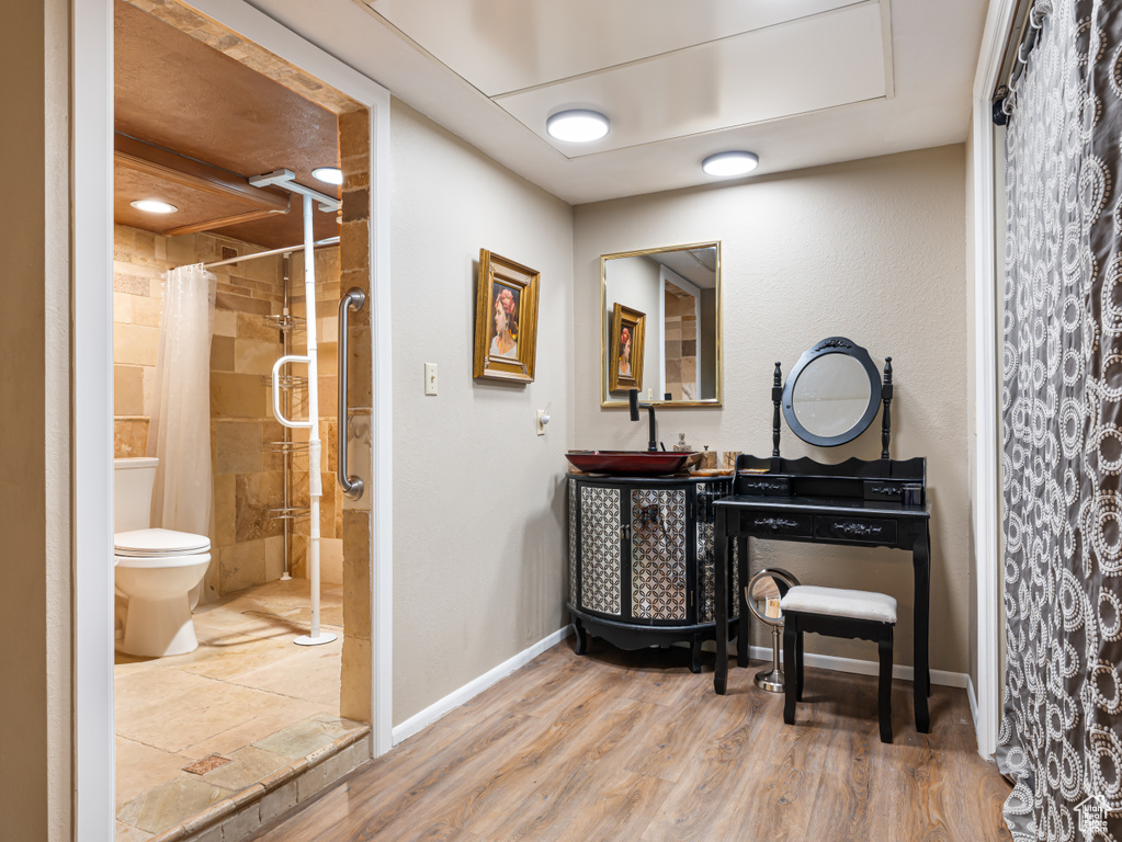 Bathroom with a shower with curtain, vanity, wood finished floors, baseboards, and toilet