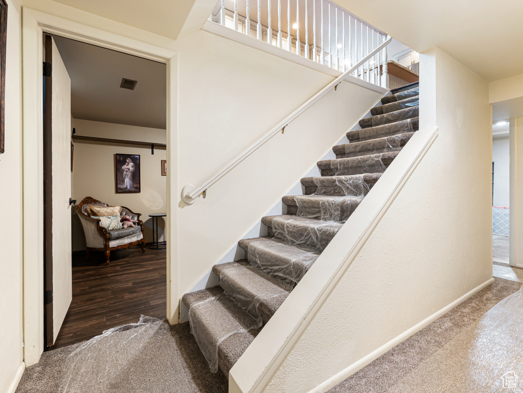 Staircase featuring baseboards, carpet, and wood finished floors