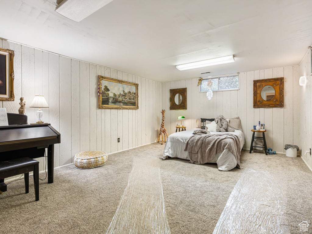 Carpeted bedroom featuring wooden walls