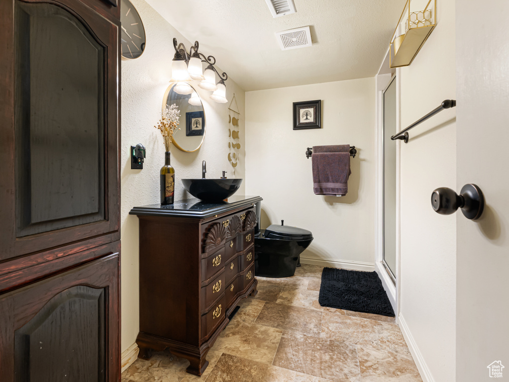 Full bath with baseboards, stone finish flooring, vanity, a stall shower, and toilet