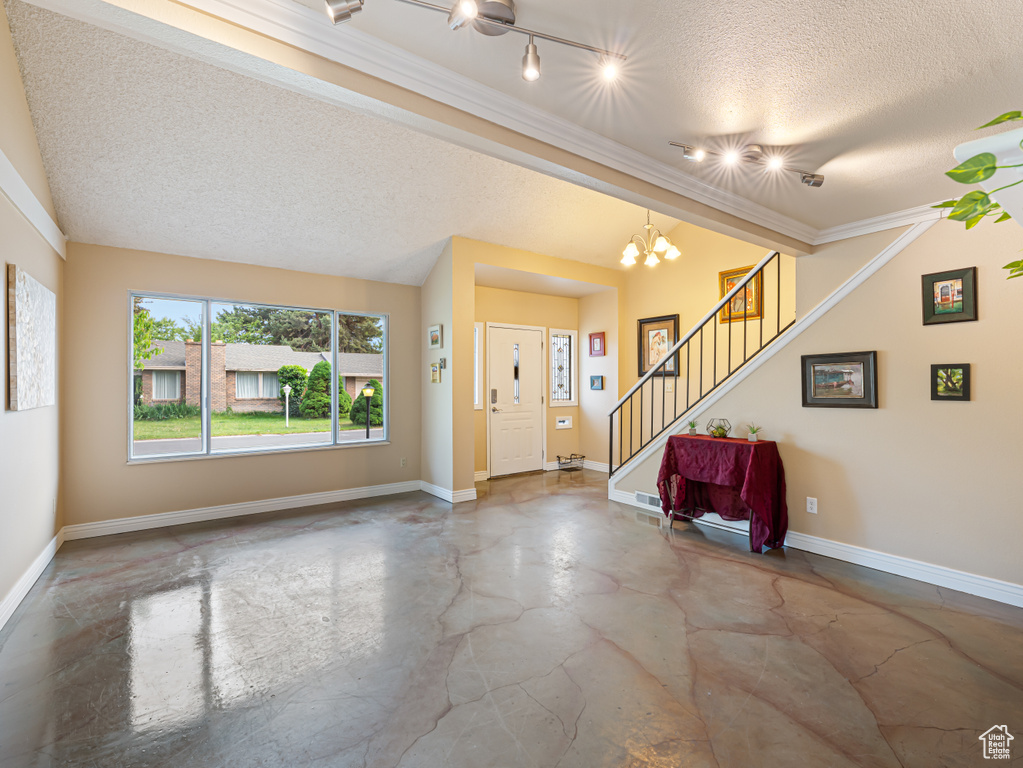 Foyer entrance featuring finished concrete floors, a textured ceiling, stairway, baseboards, and a chandelier