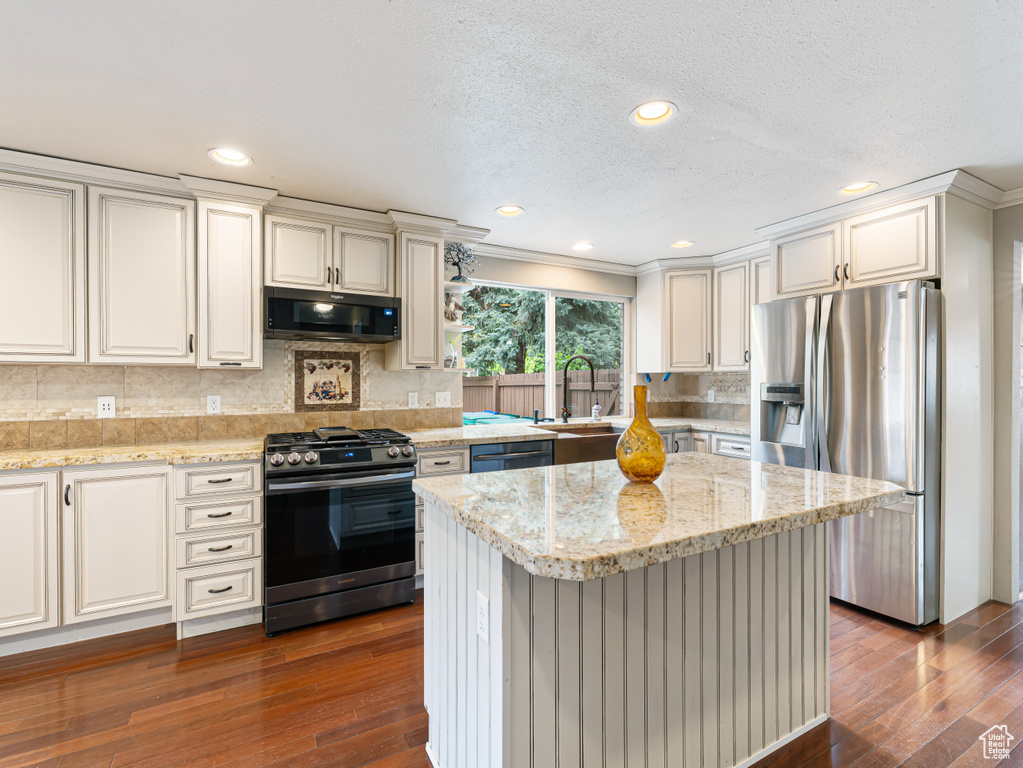 Kitchen with stainless steel appliances, a sink, dark wood finished floors, crown molding, and decorative backsplash
