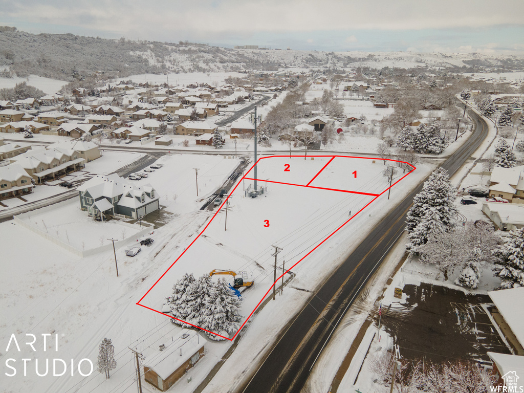 Snowy aerial view with property parcel outlined and a residential view