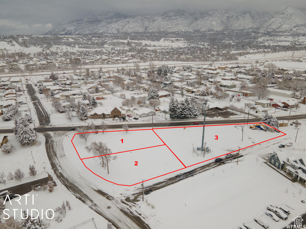 Snowy aerial view with a mountain view, property parcel outlined, and a residential view