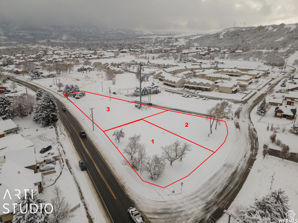 Snowy aerial view with a mountain view, a residential view, and property boundaries highlighted